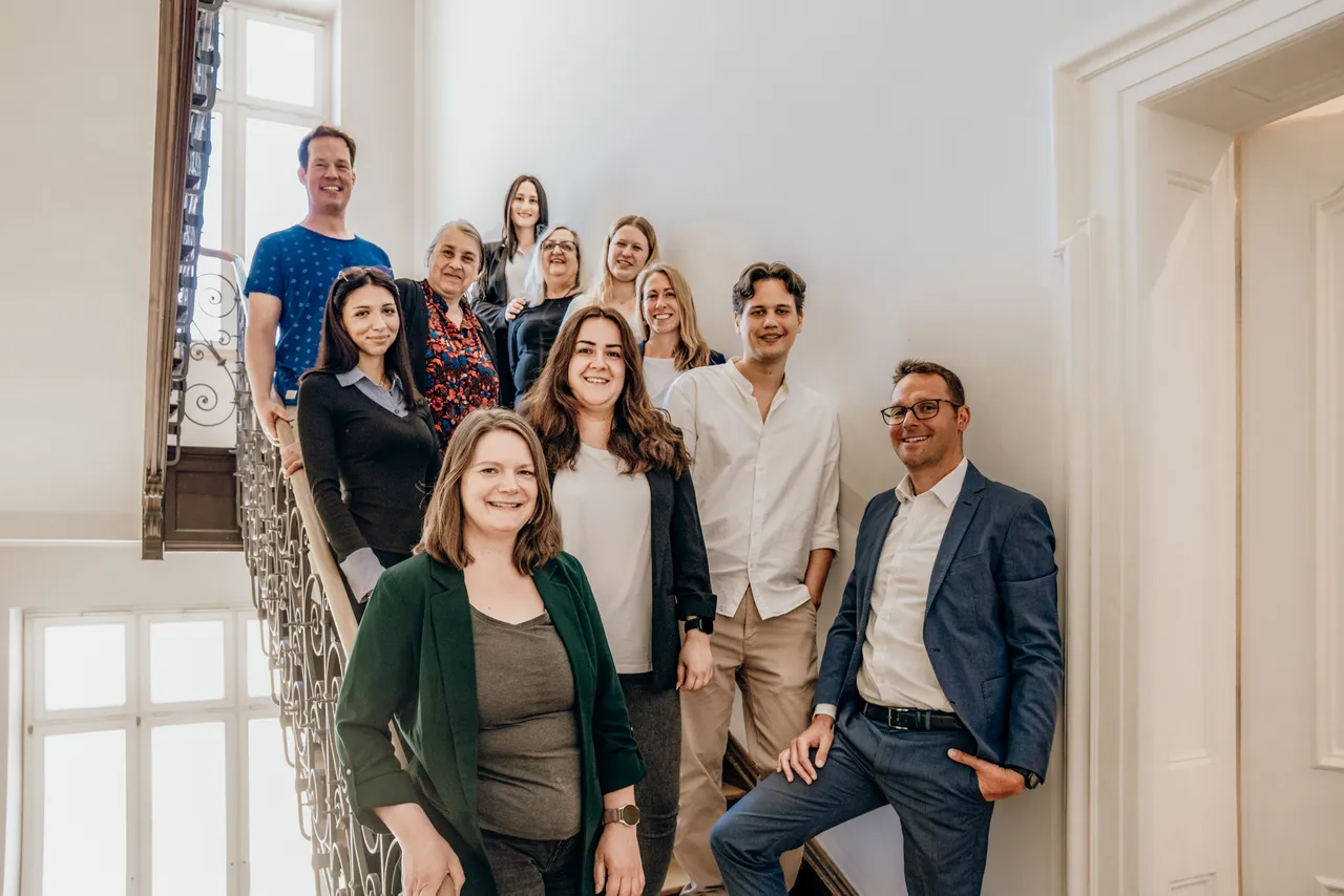 Team von RIFA im Treppenhaus des Altbaus in der Widenmayerstraße